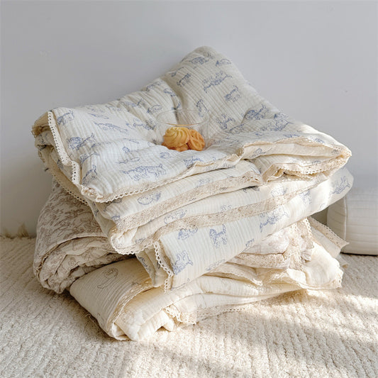 Stack of soft cotton muslin animal theme comforters for kids, featuring lamb, kitty, and woodland prints, finished with delicate lace trim