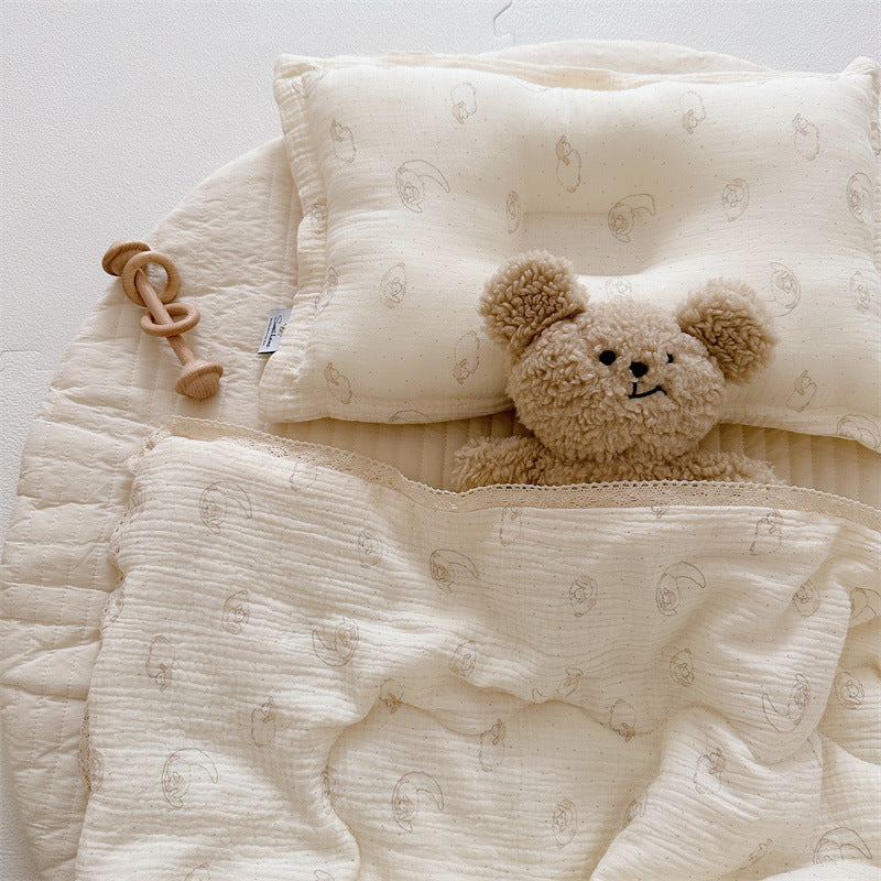 Lamb print cotton muslin comforter and matching pillow for kids, styled with plush bear toy on a round quilted mat