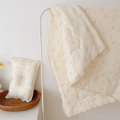 Lamb print comforter and pillow, made from airy cotton muslin with lace trim, hanging and displayed in a bright nursery.