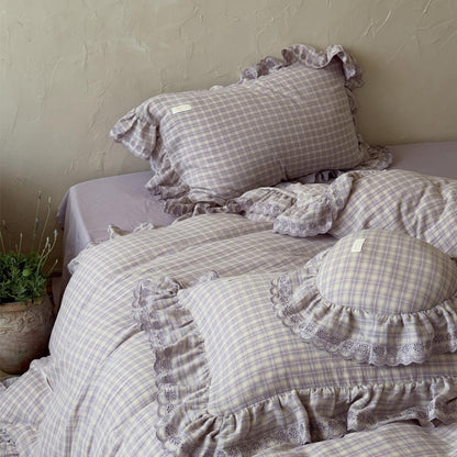 Top-down view of lavender plaid bedding and pillows with book and candle