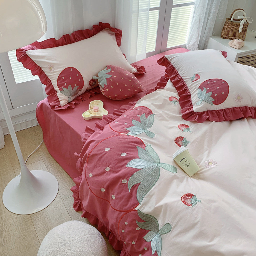 Bed with strawberry-themed bedding in a bright room