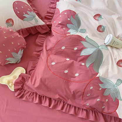 Pink strawberry-themed bedding set with matching pillows on a bed.