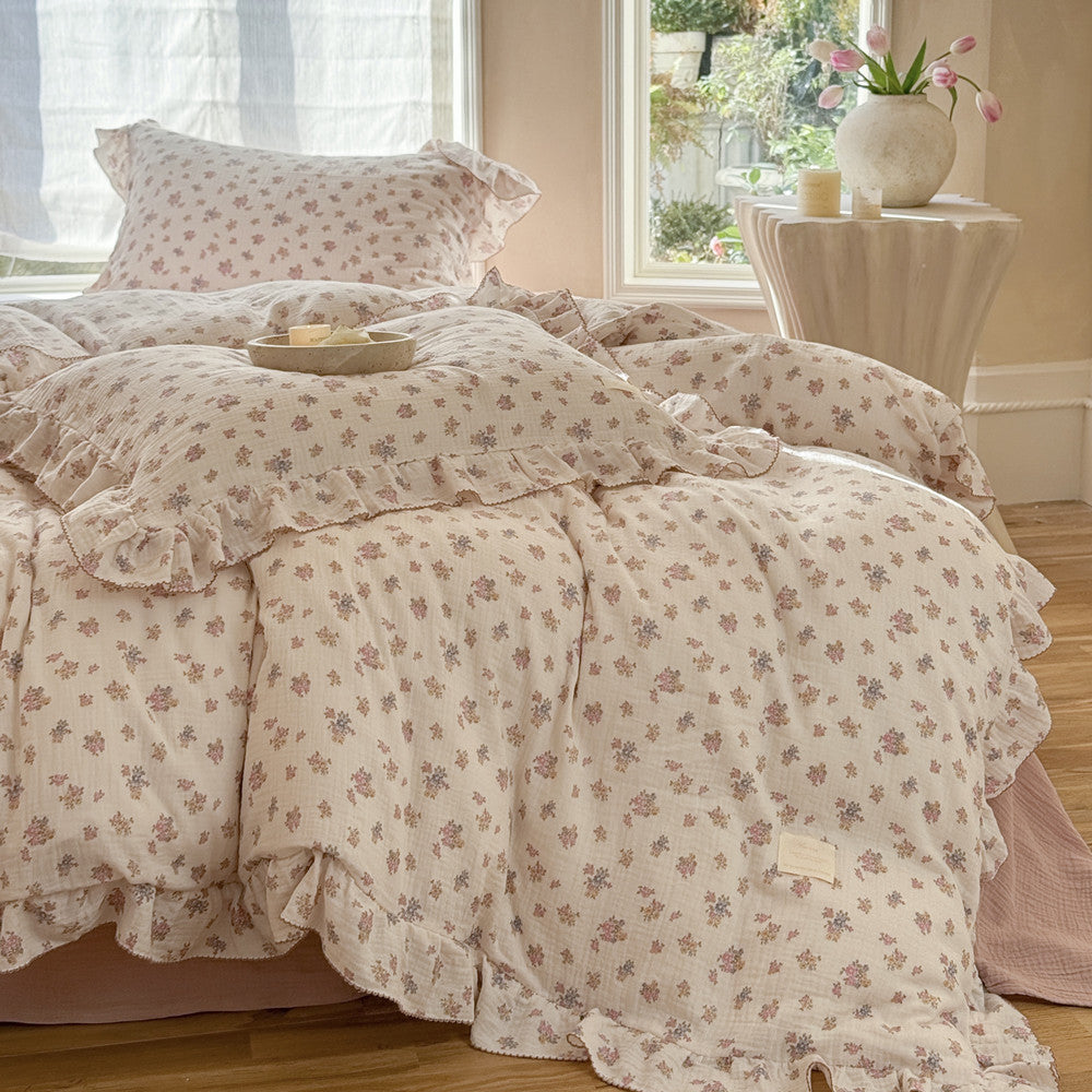 Full view of Tuberose Floral Cotton Muslin Duvet Cover Set on a bed, showing the ruffled edges, matching pillow shams, and a pink sheet underneath, highlighting the cozy cottagecore style.