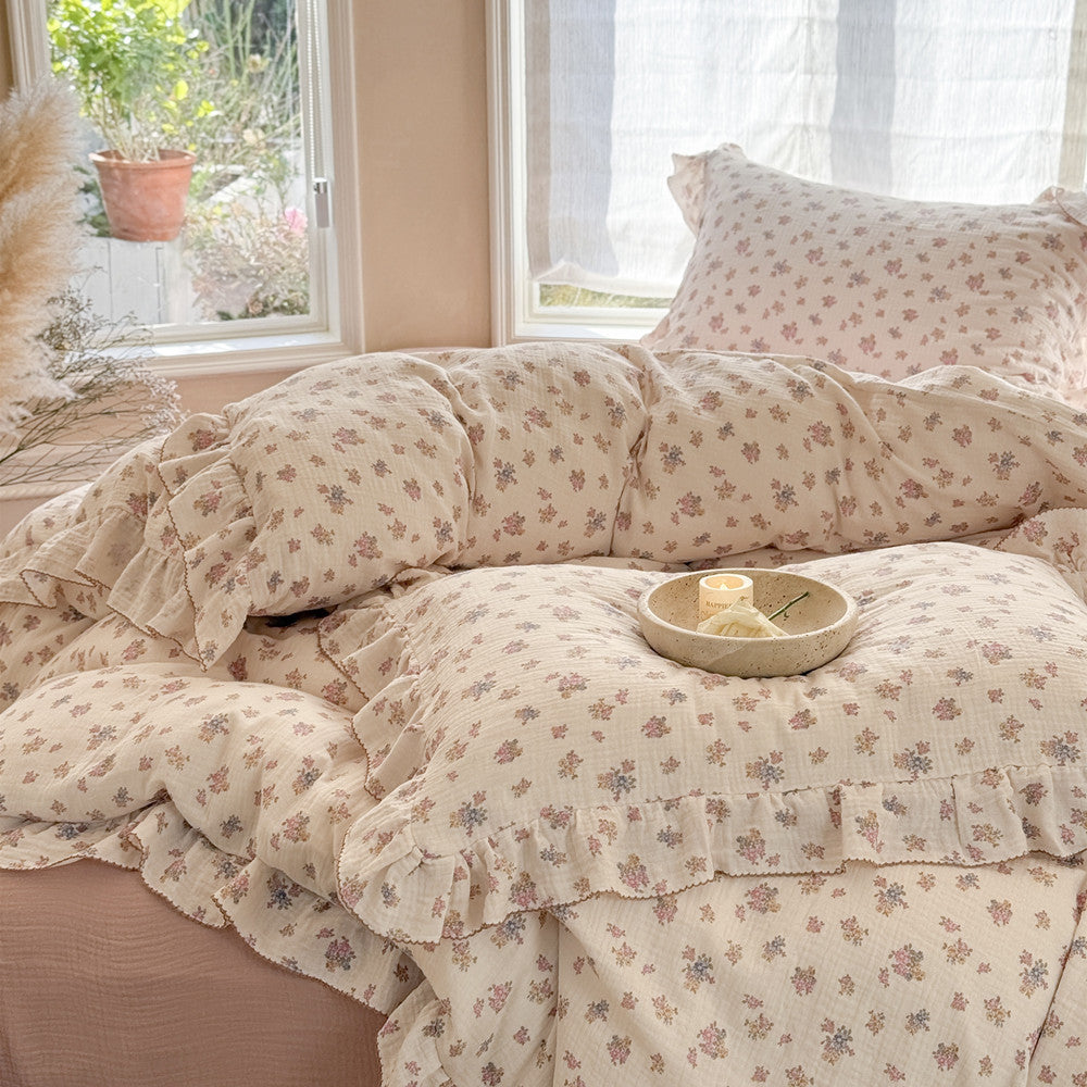 Styled shot of the Tuberose Floral Ruffled Muslin Bedding Set on a bed, highlighting the relaxed, airy texture and feminine cottage chic look with a small decorative tray on top.