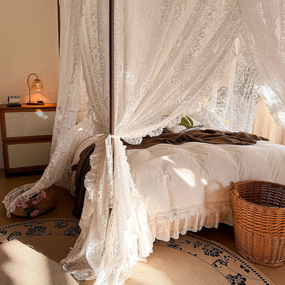 Bedroom with a canopy bed draped in lace curtains, wooden nightstand, and decorative items.