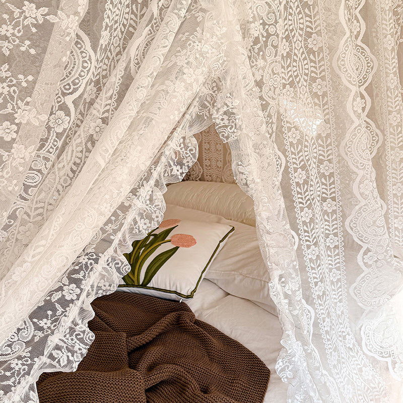 Lace canopy over a bed with pillows and a blanket