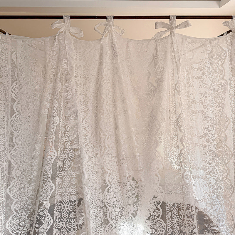 Lace curtains with decorative bows hanging against a neutral background