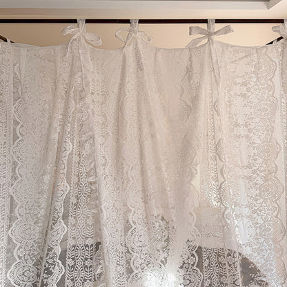 Lace curtains with decorative bows hanging against a neutral background