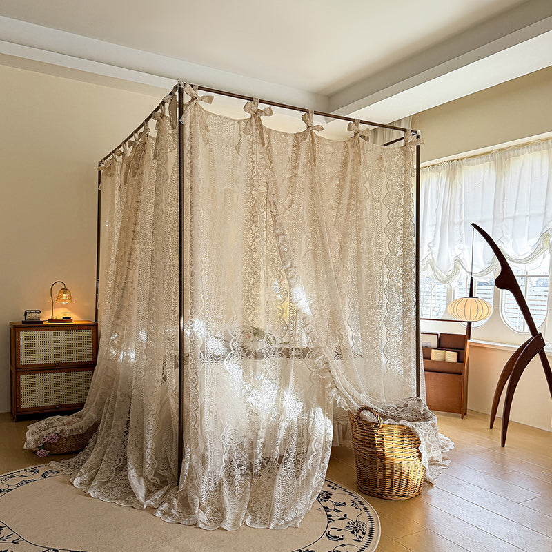 Lace canopy bed in a room with a lamp and chair.