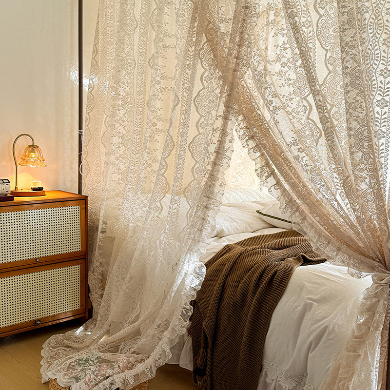 Lace curtains in a bedroom with a wooden nightstand and lamp.