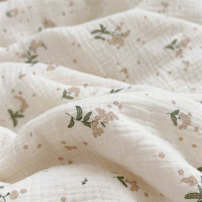 Close-up shot of a crinkled cotton muslin baby blanket with a delicate floral print.