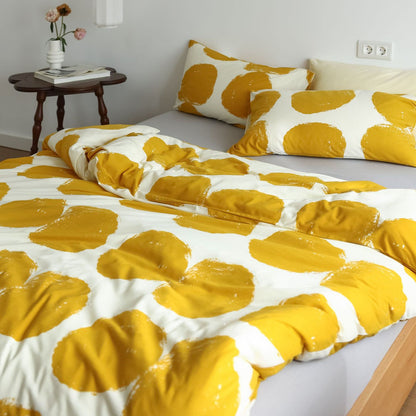 Close-up view of yellow polka dot pattern and cotton jersey fabric on duvet cover with gray sheet