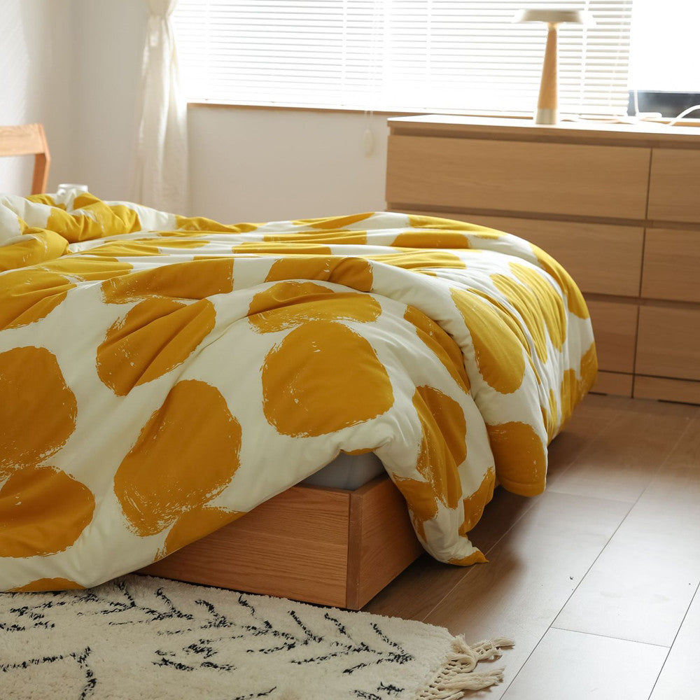Detail of duvet cover edge draped over bed showing texture, yellow dots, and included gray sheet