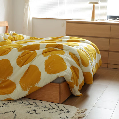 Detail of duvet cover edge draped over bed showing texture, yellow dots, and included gray sheet