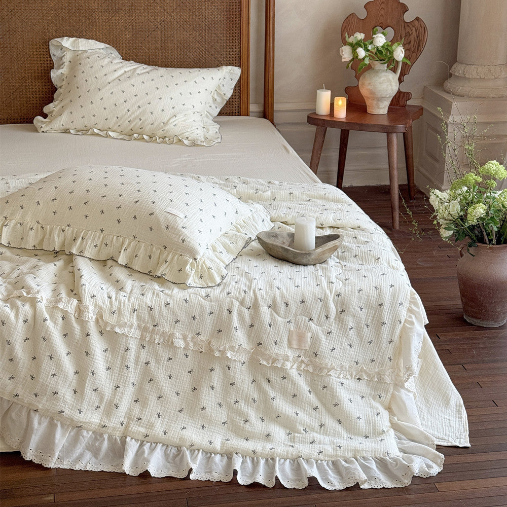 Lightweight ruffled cotton comforter and matching bow pillow styled with candles
