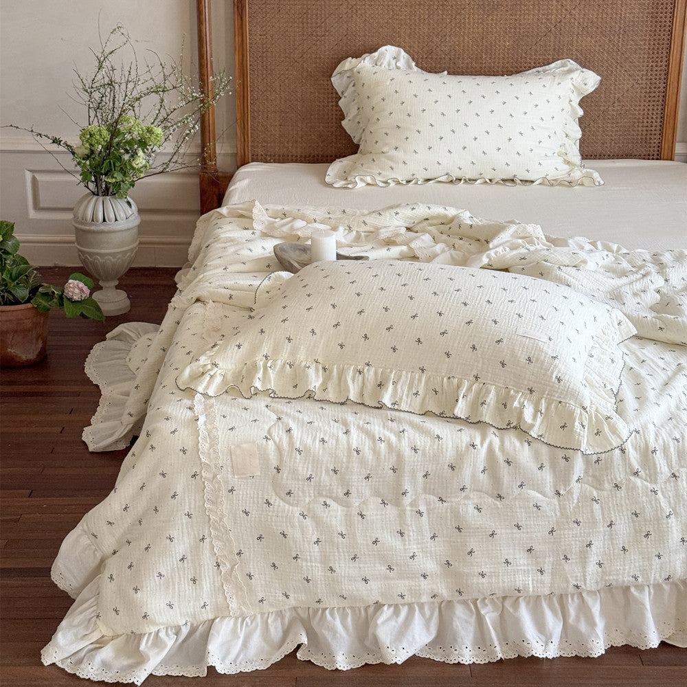 Girly cotton comforter with bow print styled on a child’s bed with greenery