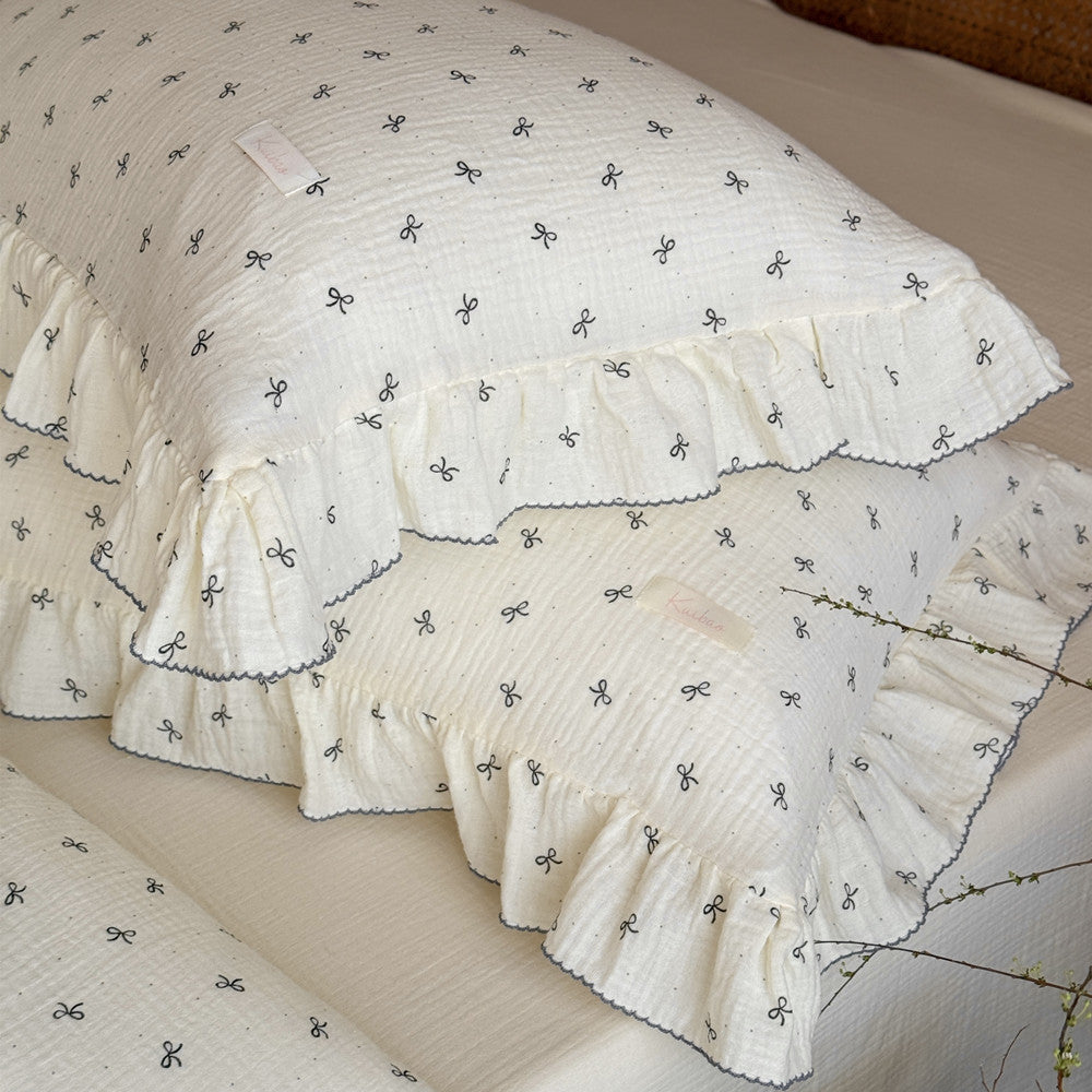 Ivory bow comforter with ruffled pillows styled in cottage bedroom