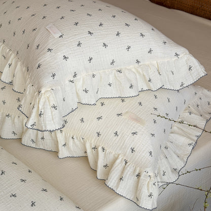 Ivory bow comforter with ruffled pillows styled in cottage bedroom