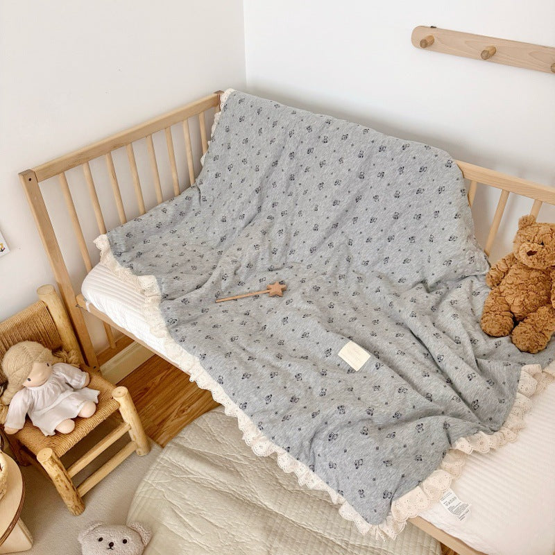 Grey jersey baby comforter laid out in crib