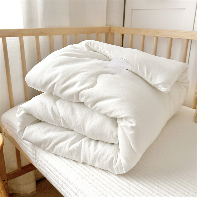 Toddler comforter insert and matching pillow displayed on wooden bed frame, ready for duvet cover pairing