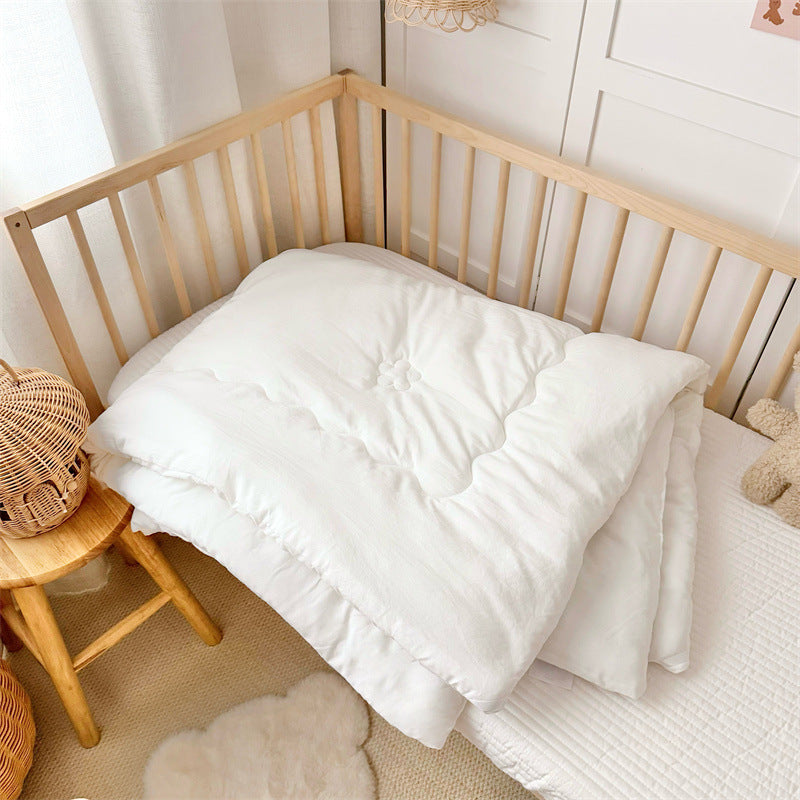 Lightweight toddler inner quilt in clean white, styled with neutral bedding setup for versatile use