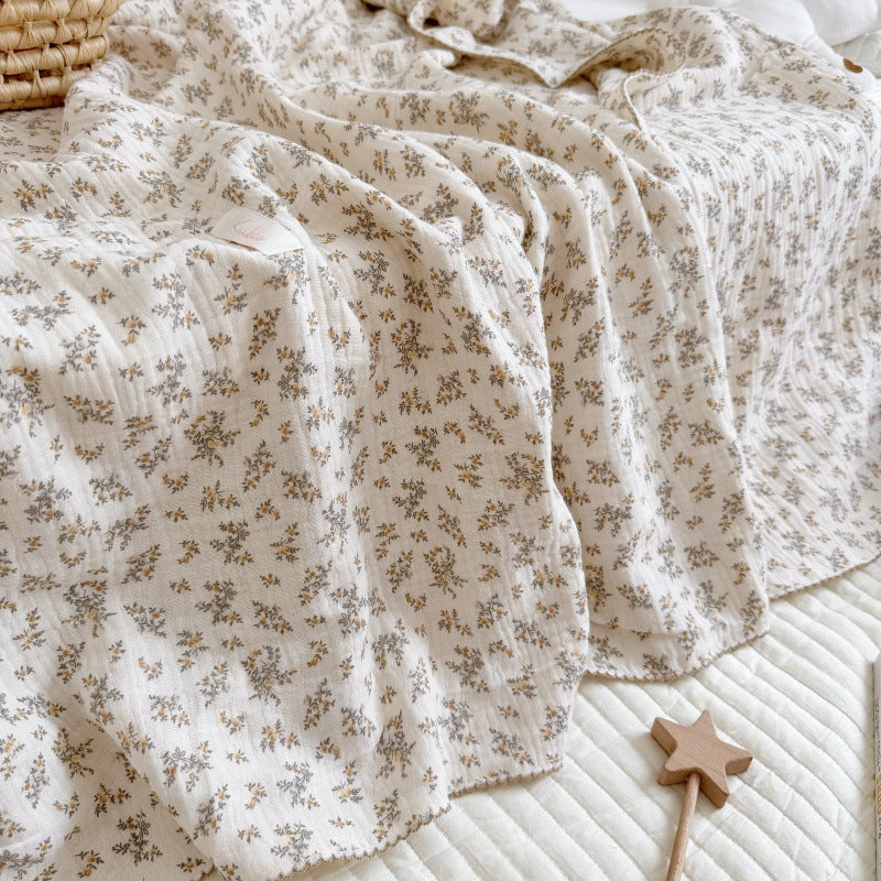 An Osmanthus floral print crinkled muslin blanket laid on a bed, showcasing its soft texture and natural drape.
