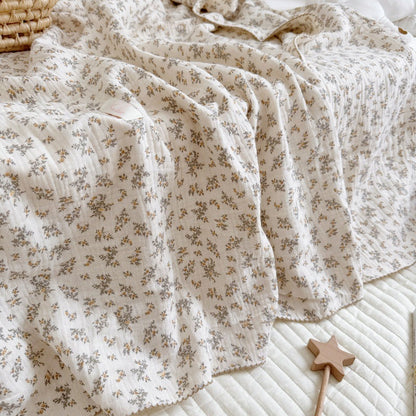 An Osmanthus floral print crinkled muslin blanket laid on a bed, showcasing its soft texture and natural drape.