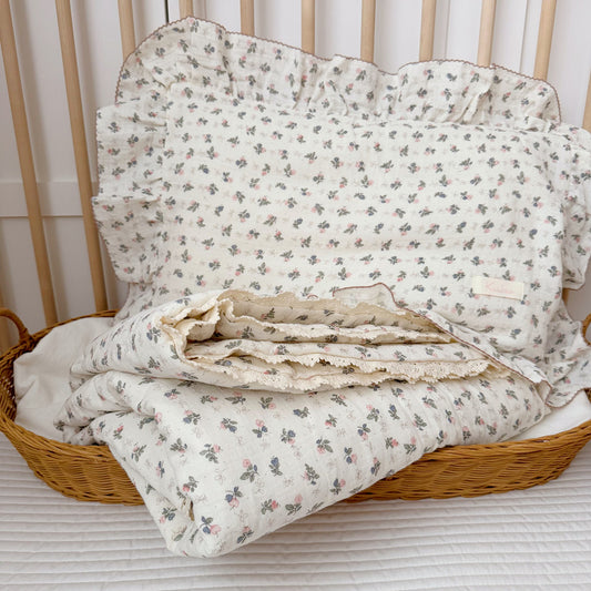 Folded small pink floral comforter and matching pillow in wicker basket