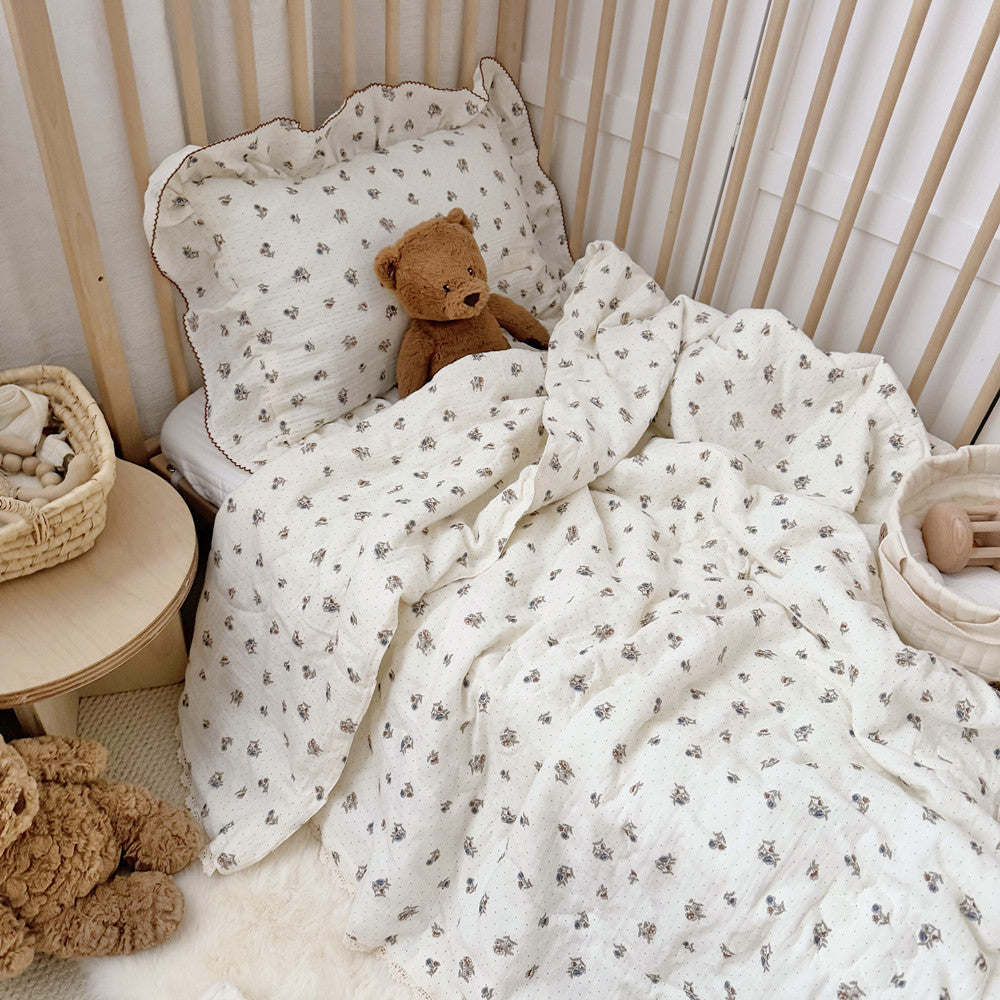 Teddy bear tucked into crib with comforter