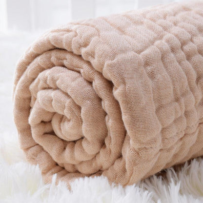 Close-up of a rolled-up 6-layer organic colored cotton muslin baby blanket, highlighting the plush, thick and soft texture.